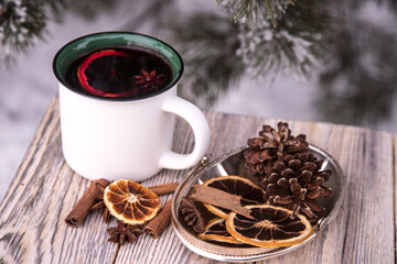 Close-up of mugs with mulled wine and spices on a wooden table in winter.