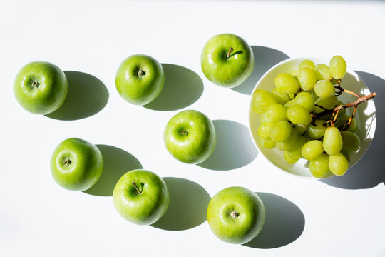 top view of apples near tasty grapes in bowl on white.