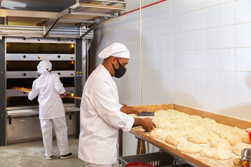 Portrait of confident latin american bakery owner engaged in breadmaking, preparing portioned...