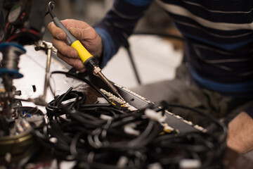 Industrial worker man soldering cables of manufacturing equipment in a factory. Selective focus