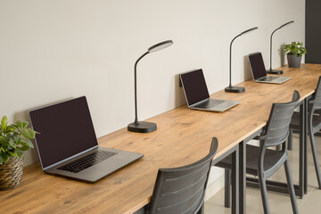 Several laptops standing in a row on a wooden tabletop. Workplaces.