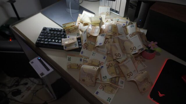 Tirando Dinero Muchos billetes de euro encima de una mesa con ordenador en el despacho