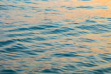 Unfocused blue, pink, yellow, orange, lilac sea waters ripple texture. Natural abstract sunset sea background