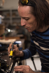 Industrial worker man soldering cables of manufacturing equipment in a factory. Selective focus