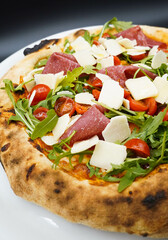 Una pizza tipica napolitana con jamon curado, queso parmesano y rucula, hecha con masa madre