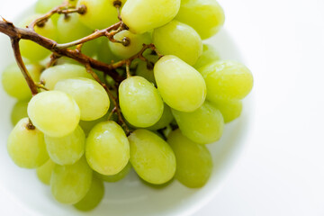 close up view of fresh grapes in bowl on white.