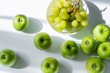 top view of bowl with sweet grapes and apples on white.