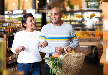 Portrait of happy couple with bag full of groceries in supermarket interior