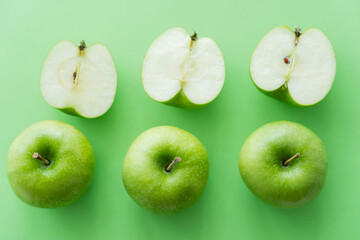 flat lay of tasty whole and cut apples on green.