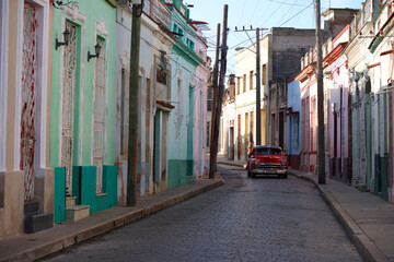 Fototapeta na wymiar Street with its colorful houses and one old car in the middle, Camaguey, Cuba