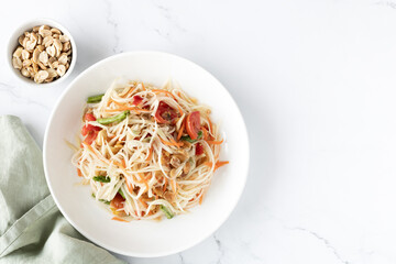 Papaya salad on a white plate, top view. Traditional Asian street food. Thai cuisine top view, copy space.