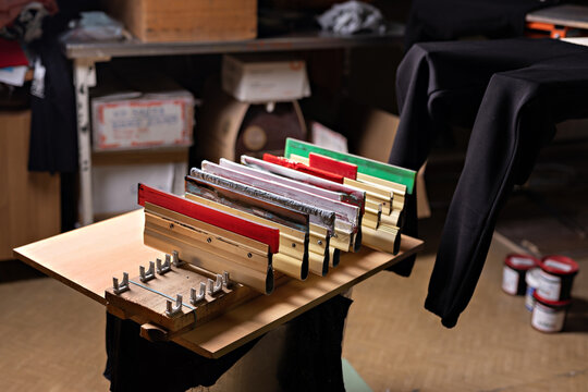 squeegees on wooden desk. serigraphy production. printing images on t-shirts by silk screen method in a design studio