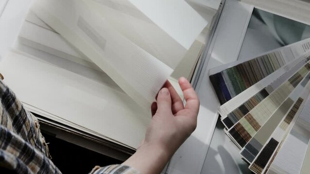 Woman fliping through catalog with roller blinds or window shade. Duo window roller system day and night. Choice of roller blinds.