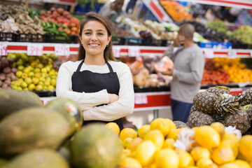 Portrait of positive female merchandiser with melon in hands at grocery supermarket