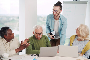 Obraz premium A hipster educator is showing a lesson on the tablet to a multicultural group of senior students in the classroom.
