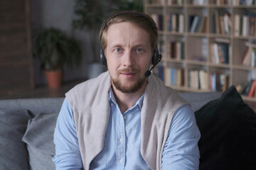 Portrait of confident European guy in headset call to friends talking online video lesson distance...