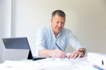 Business portrait of architect sitting at his work table and planning in his modern bright office
