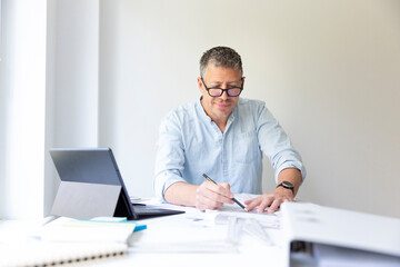 Business portrait of architect sitting at his work table and planning in his modern bright office