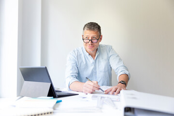 Fototapeta premium Business portrait of architect sitting at his work table and planning in his modern bright office