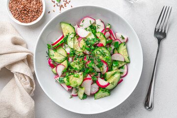 A portion of salad with radishes on a gray background. Top view, close-up.