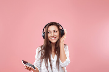 Cute girl uses wireless earphones and dancing. Beautiful woman listening to music using wireless headphones.
