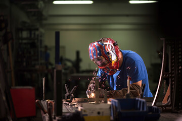 Professional Heavy Industry Welder Working Inside factory, Wears Helmet and Starts Welding. Selective Focus