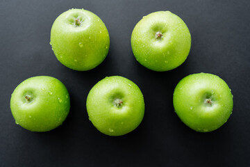 flat lay of green and fresh apples with water drops on black.
