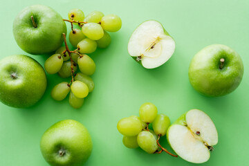 top view of apples and ripe grapes on green.