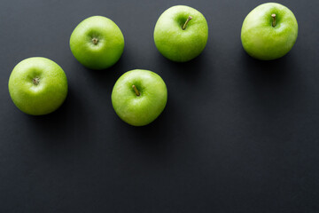 top view of fresh and green apples on black.