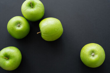 top view of ripe and green apples on black.
