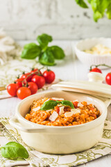 Homemade tomato risotto with fresh basil on a white wooden table