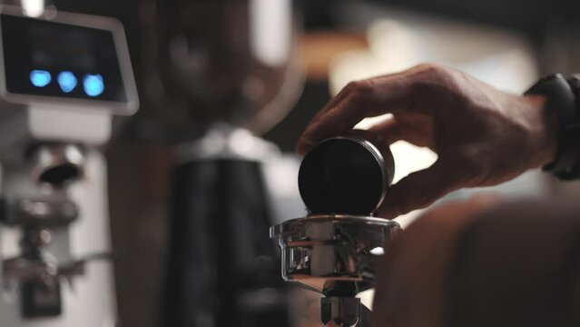 Professional barista worker use grinder machine to grind fresh coffee beans for make hot beverage at coffee cafe shop.