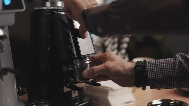Professional barista worker use grinder machine to grind fresh coffee beans for make hot beverage at coffee cafe shop.