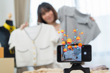 Young Asia lady fashion designer using mobile phone receiving purchase order and showing clothes...
