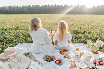 Mother and daughter on picnic in field.