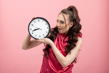 Deadline, time has run out. Woman showing clock poses standing against pink backdrop of studio. Shocked girl running late. The concept of time running out.