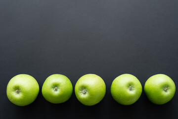 top view of fresh and green apples in row on black.