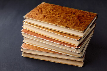 Stack of vintage dilapidated books on a dark concrete table