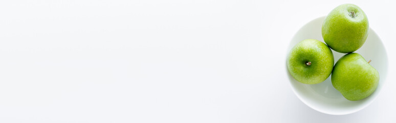 top view of green apples in bowl on white, banner.