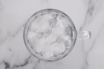 drinking enough water or sobriety concept, pint glass with tap water and ice cubes over marble background