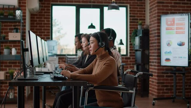 Call center employee using headset to talk to clients on helpline, working in disability friendly office. Woman having conversation with people at customer service care. Telework support.