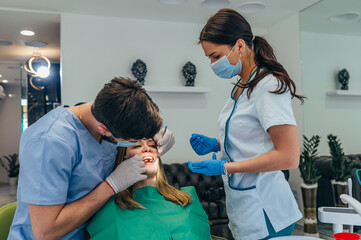 Woman patient in dental clinic being examined by a male dentist