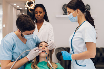 Woman patient in dental clinic being examined by a male dentist