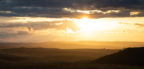 amazing sunset sky over green hills in early summer
