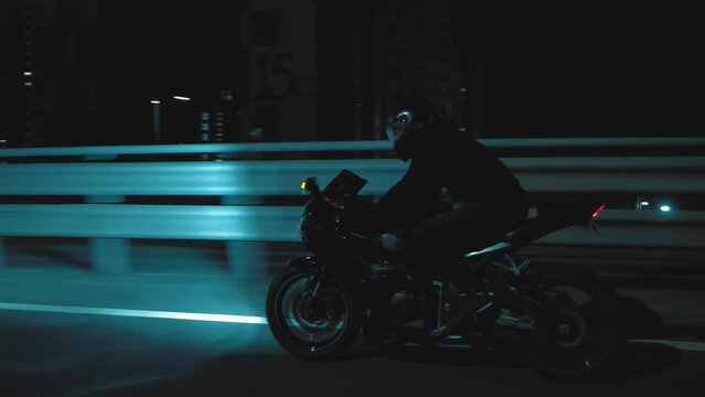 A man rides a sports motorcycle through the city at night