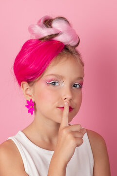 charming little girl with pink hairstyle and pink makeup. tween young model posing on pink background