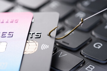 Credit card on fishing hook pulled from stack on keyboard, phishing scam data theft concept - 502923422