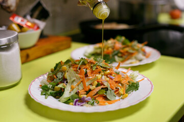 Aderezando ensalada variada con aceite de oliva virgen, plato vegano
