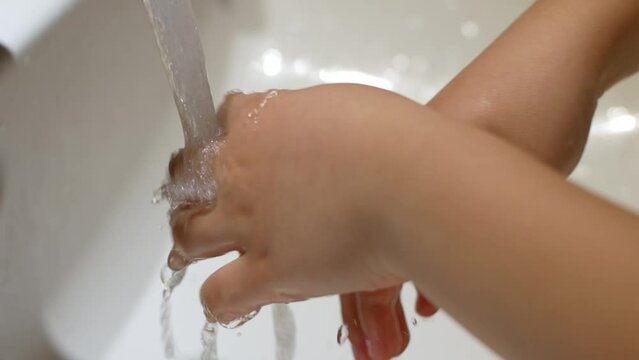 The child washes his hands under crystal clear water