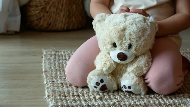 A little girl is holding a teddy bear.